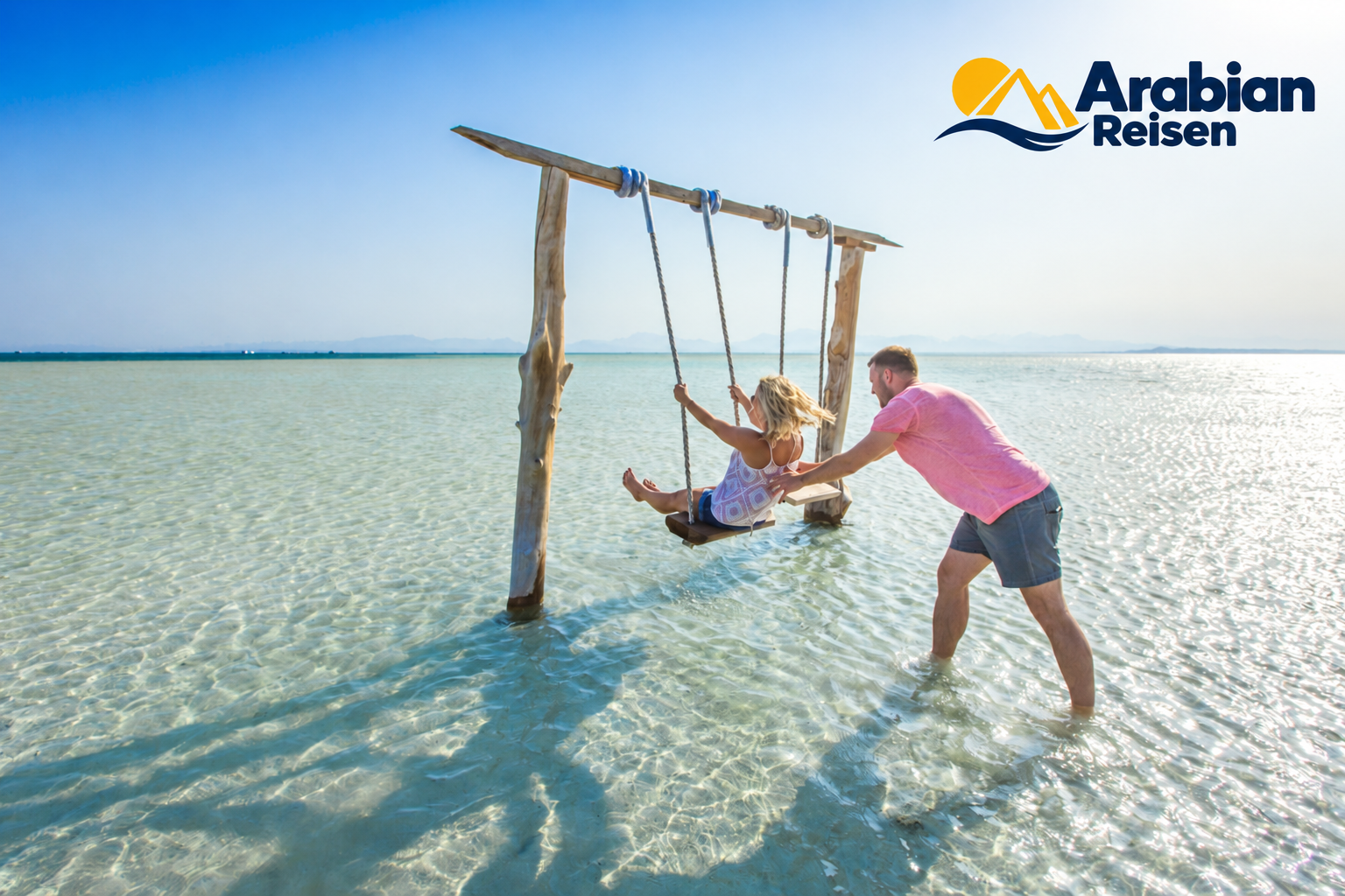 Visitors enjoying the clear Red Sea waters with the Arabian Reisen logo
